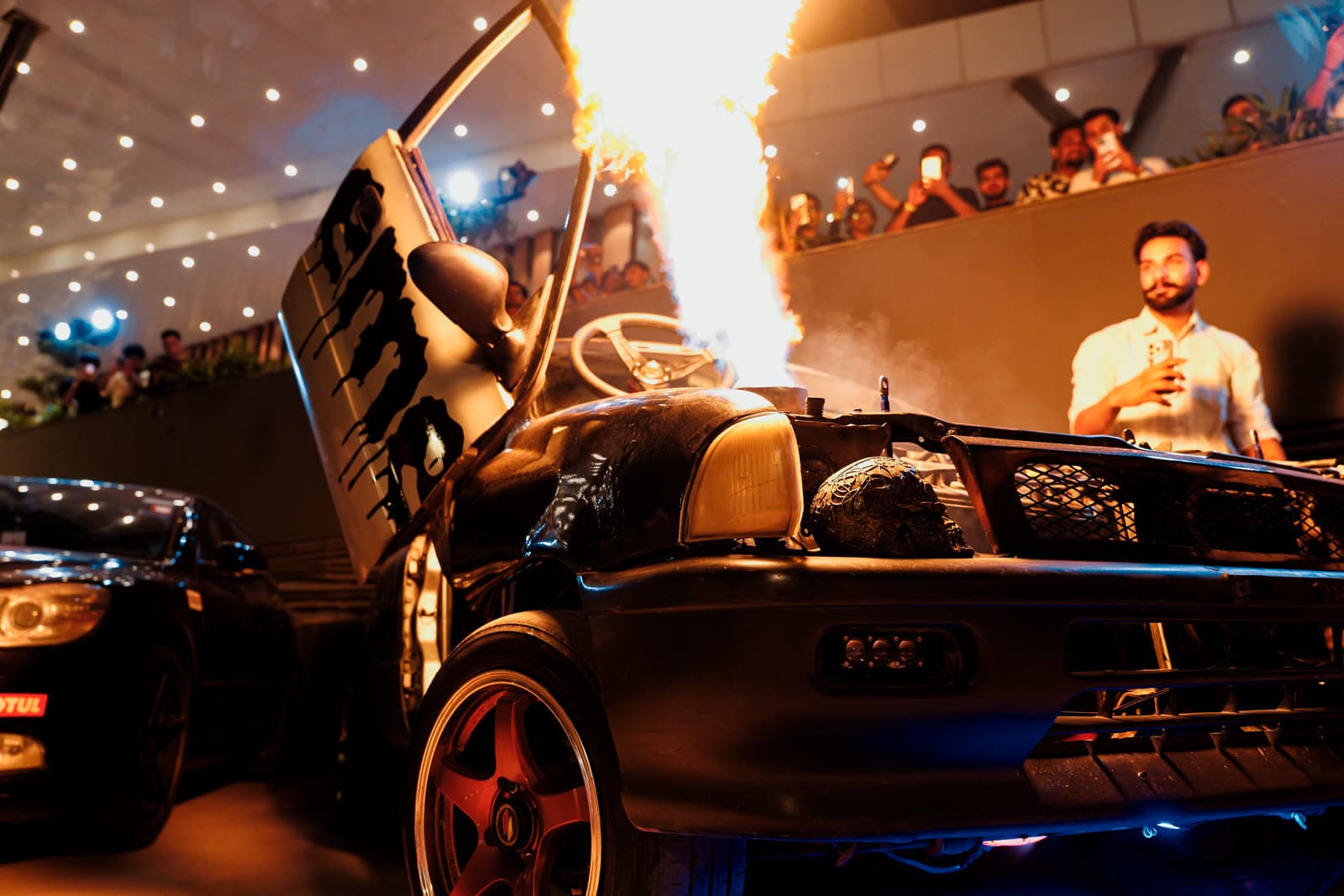 Car with doors up and a flamethrower show at night